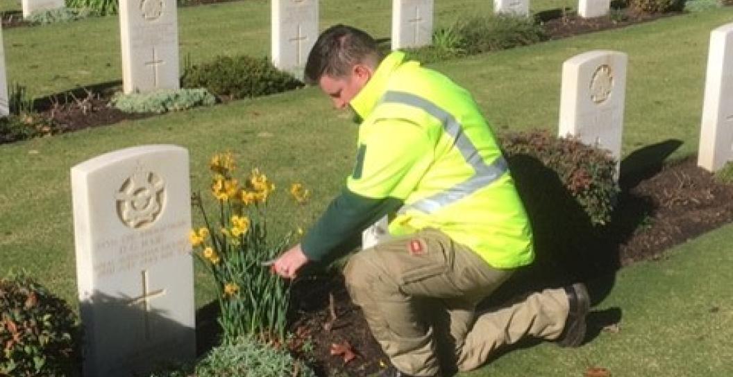 Man in high vis jacket tending a grave