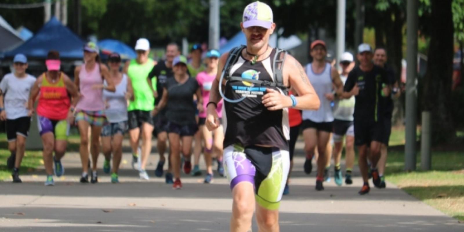 Man running towards camera with 20 or so people in group behind him