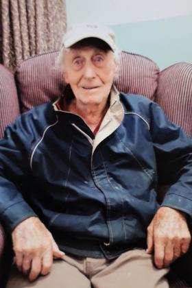 Elderly man sitting in armchair, smiling at camera