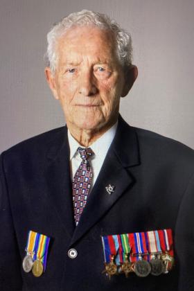 Studio portrait of elderly man in suit wearing medals on left and right breasts