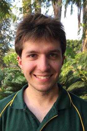 Portrait photo of young smiling man with jungle or forest behind him