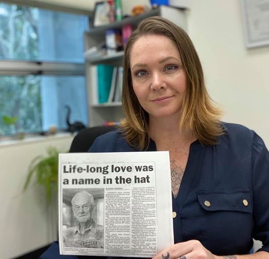 Woman holding up article that reads ‘Life longlove was a name in the hat’.